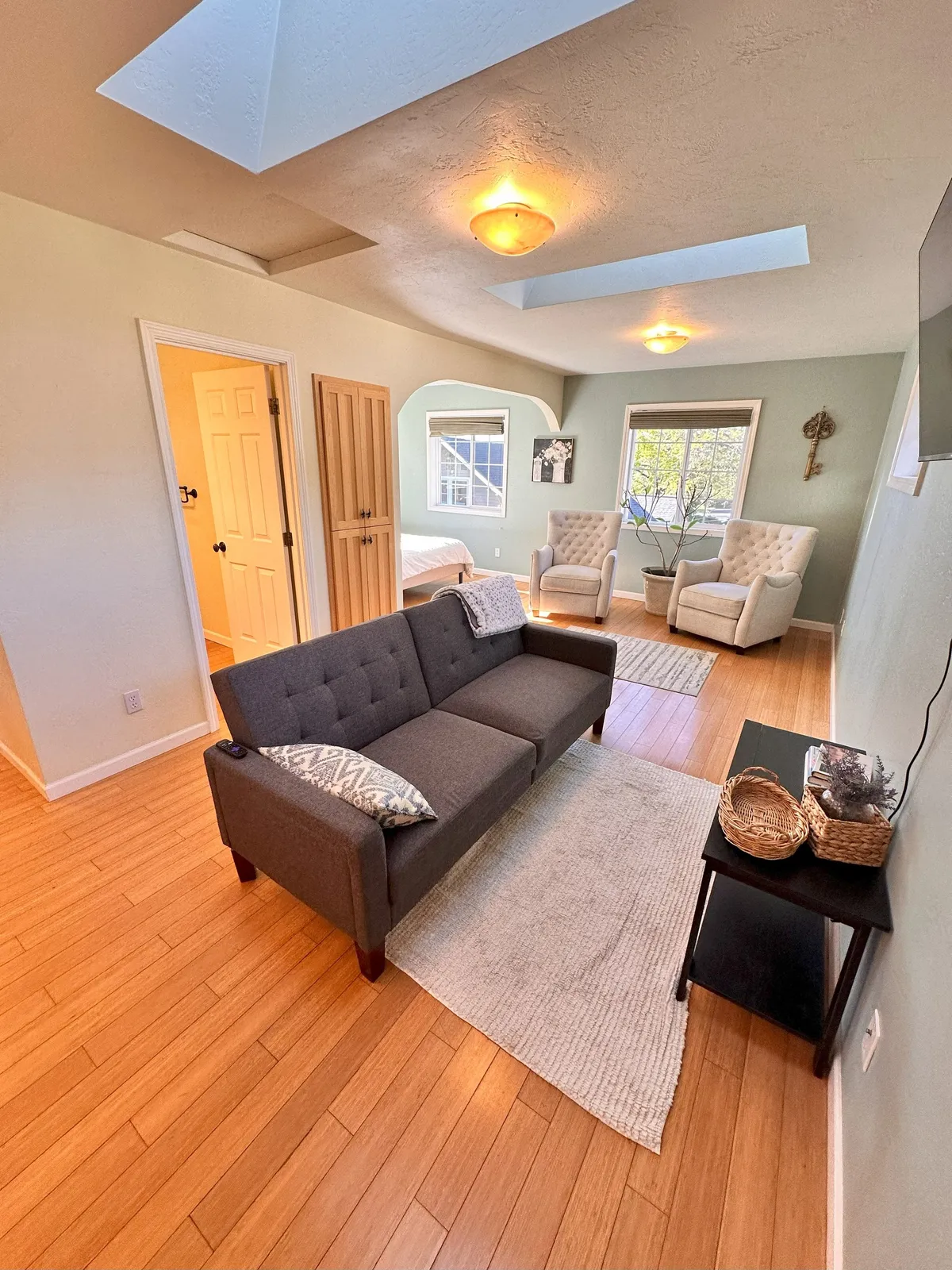 A comfortable living space featuring a sofa, chairs, window, and decorative touches. Sunlight pours through the window, illuminating a stylish rug and inviting spots for reading or enjoying a morning coffee.