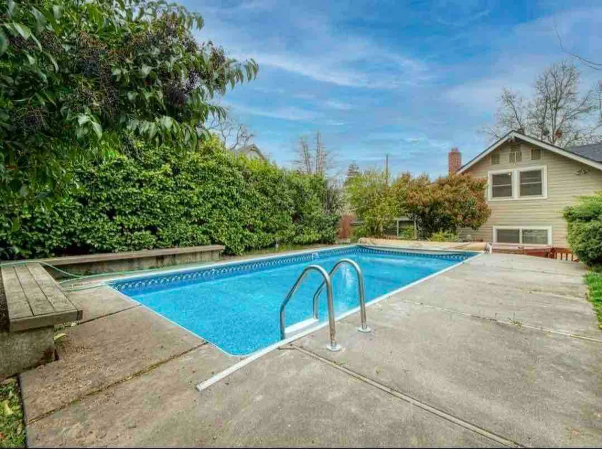 A serene swimming pool is surrounded by lush greenery and a cozy patio area, inviting guests to relax and unwind after a day of exploring. The tranquil mood underscores the restorative amenities available.