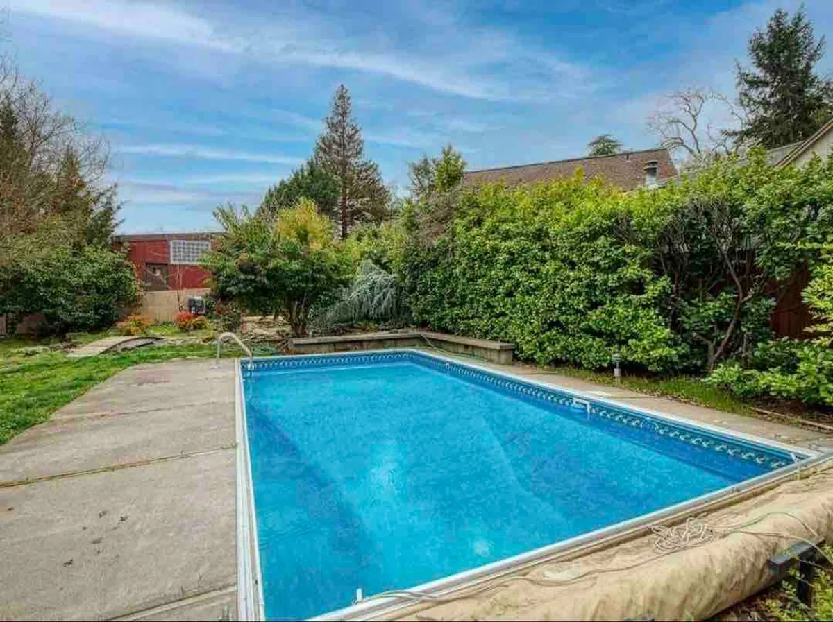 A sparkling swimming pool bordered by greenery and a spacious patio area, capturing a relaxed and peaceful mood—ideal for unwinding after a day out.